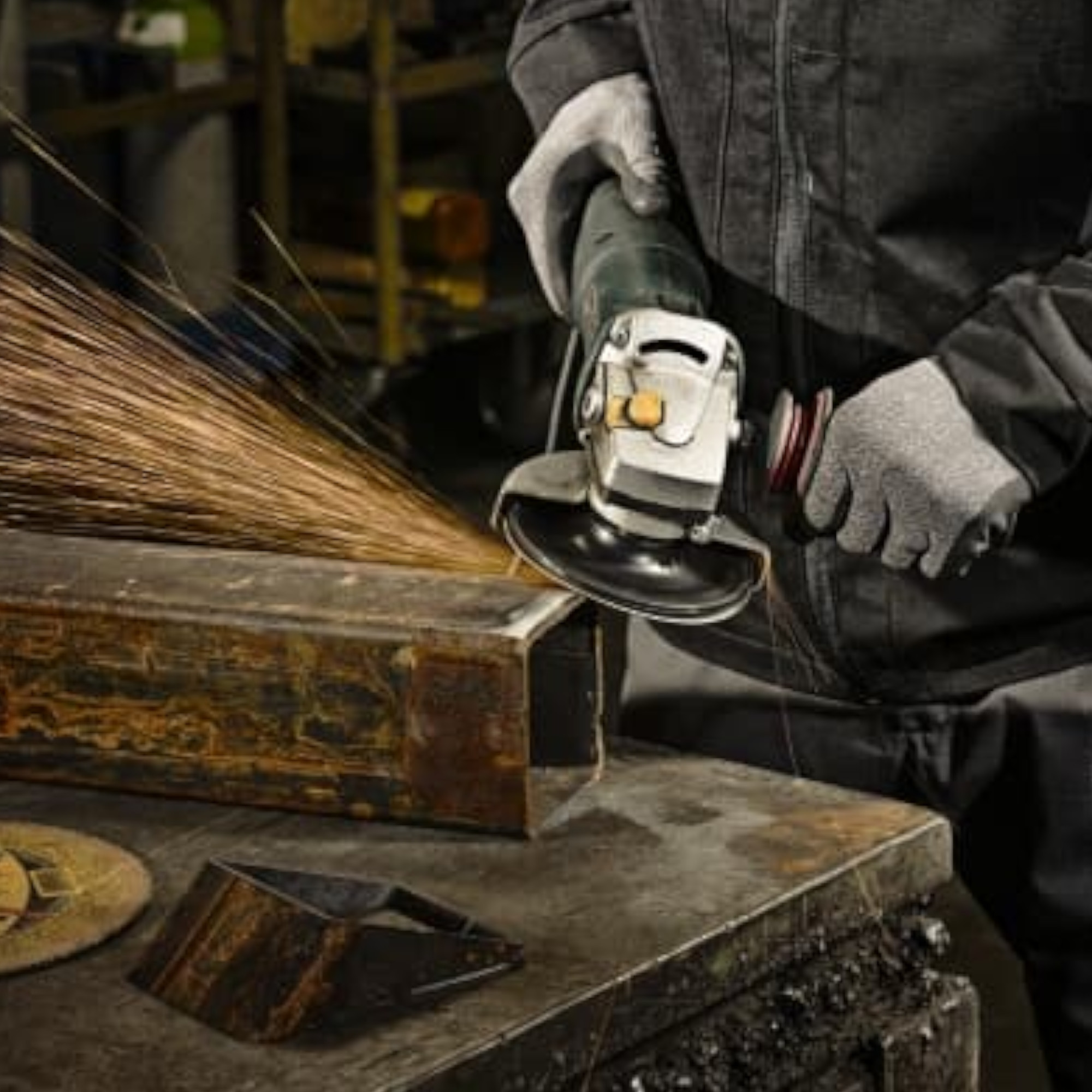 Ein Handwerker schleift einen Metallblock mit einer Schleifmaschine. Funken fliegen von der bearbeiteten Oberfläche. Die Person trägt Schutzhandschuhe und arbeitet konzentriert in einer Werkstatt.
